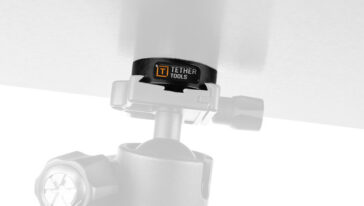 Close-up of a Tether Tools clamp attached to a stand securing a vertical pole with branding visible on the clamp surface.