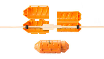 Orange modular cable lockout components around a white USB-C tether connector (TetherBoost Pro USB-C) on a cable, shown in two halves separated and a detached orange piece below — used to secure or protect the connection.