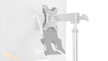Monitor attached to an adjustable mounting arm with a clamp supporting the screen and cables behind it as it appears from the back of the monitor desk setup.