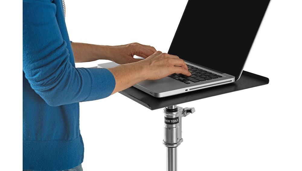 A person typing on a laptop on a low boy roller