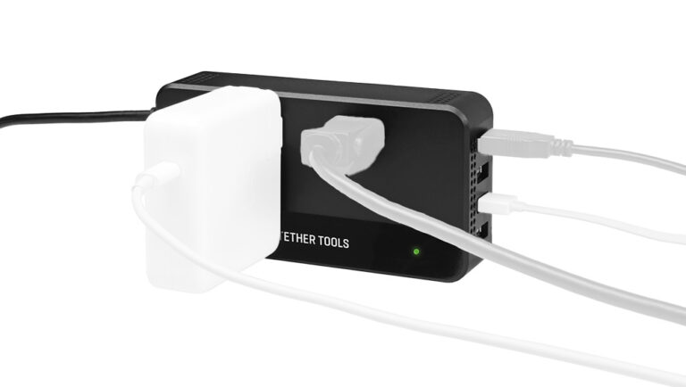 Black multi-port charging hub with several cables plugged in and a green power/status LED visible