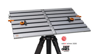 Metal camera slider mounted on a tripod with orange adjustment knobs and locking clamps; Red Dot 2026 winner logos visible on the side.