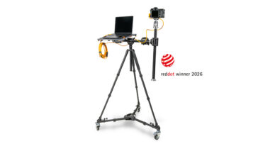 Camera rig with laptop on a wheeled stand and a mounted camera, beside a Red Dot Award 2026 logo