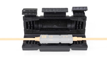 Orange fiber optic cable plugged into a gray 10 Gb connector resting in a black protective case.