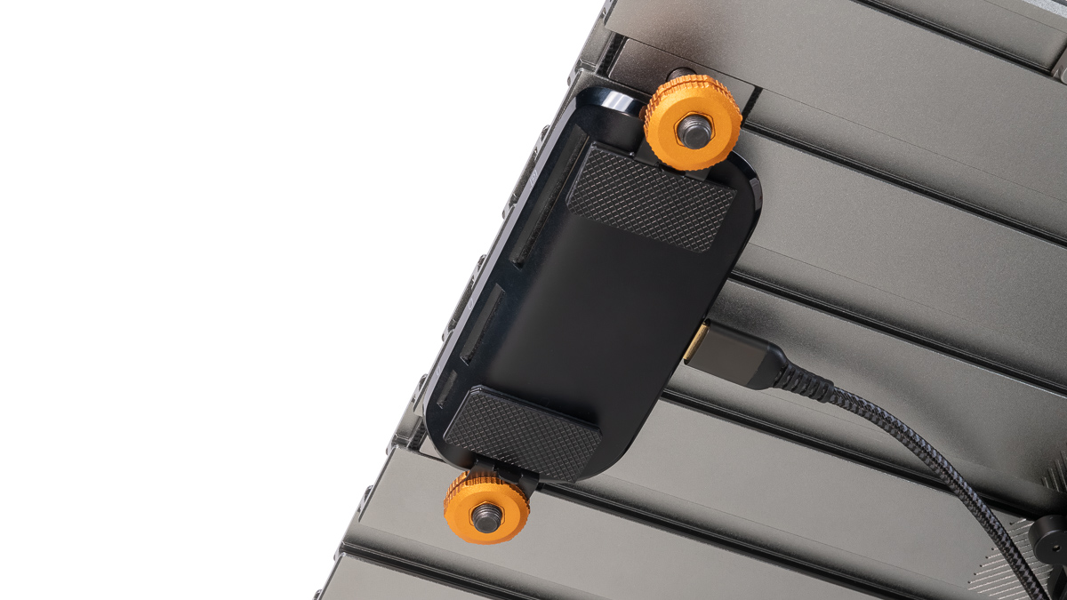 Black mounting plate with orange knurled knobs attached to a metal rack; USB-C cable plugged in.