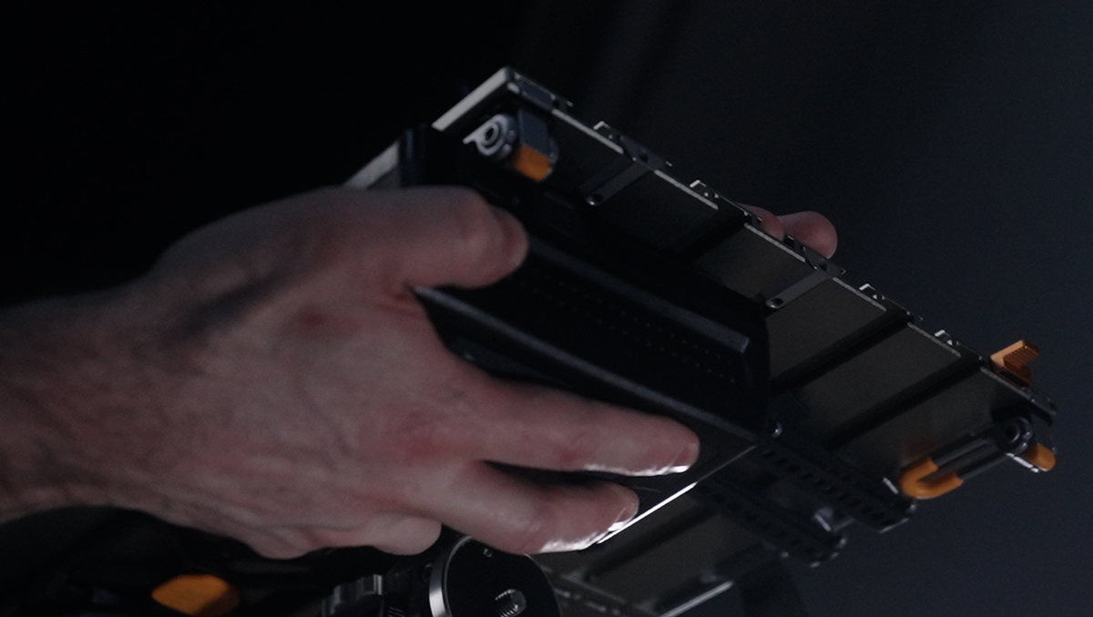 Close-up of a hand mounting a large server blade/module with orange latches.] ,