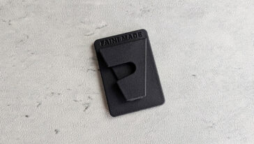 Black rectangular tag with 'FAN MADE' embossed on a gray textured surface.