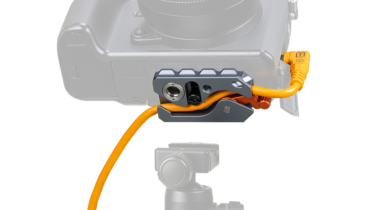 Close-up of a camera with an orange cable secured in a gray quick-release clamp accessory