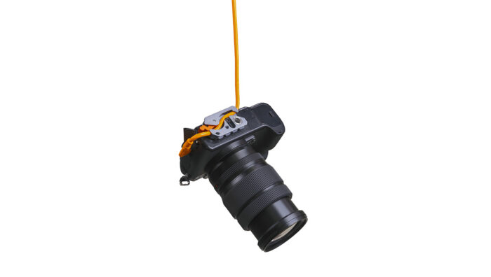 DSLR camera with a long zoom lens hanging from an orange strap against a white background