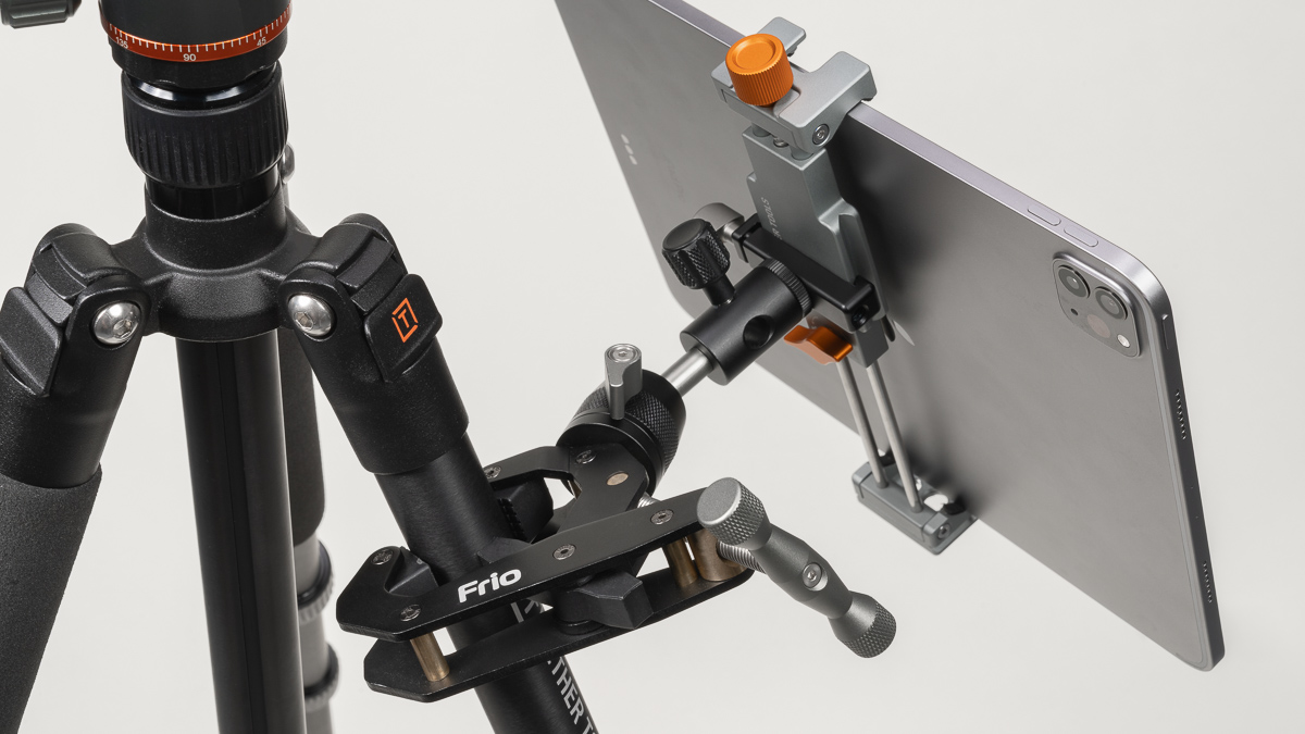 Tripod with a smartphone mounted in an adjustable clamp on a horizontal arm for stable filming/photo setup
