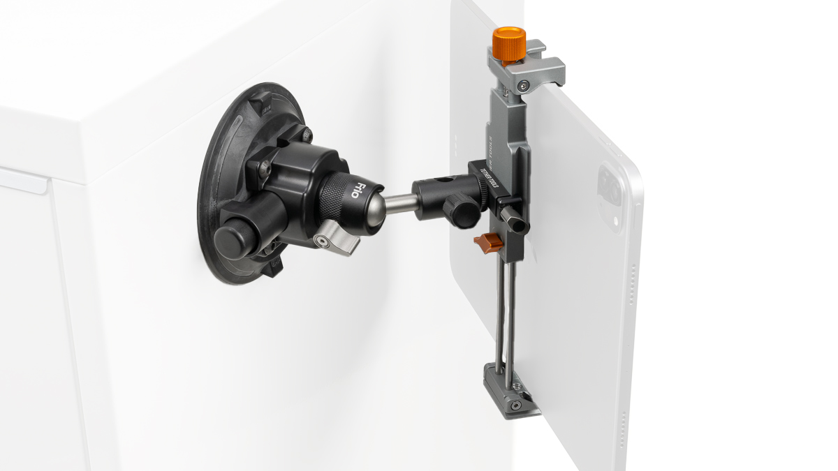 Precision alignment device mounted on a white cabinet, featuring a black dial, silver rod, and orange adjustment knob.