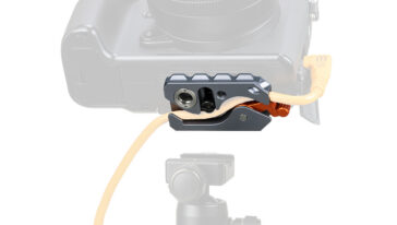 Close-up of a gray camera accessory clamp attached to the camera body, with an orange cable threaded through it.